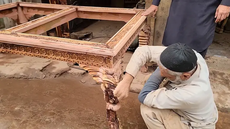 A craftsman carving a wooden frame in the Shafqat Furniture workshop